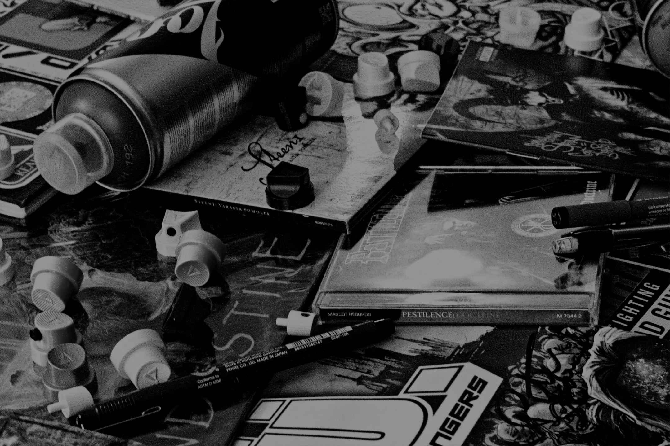 Grainy black and white picture of albums, cd's, pens and spraypaint.